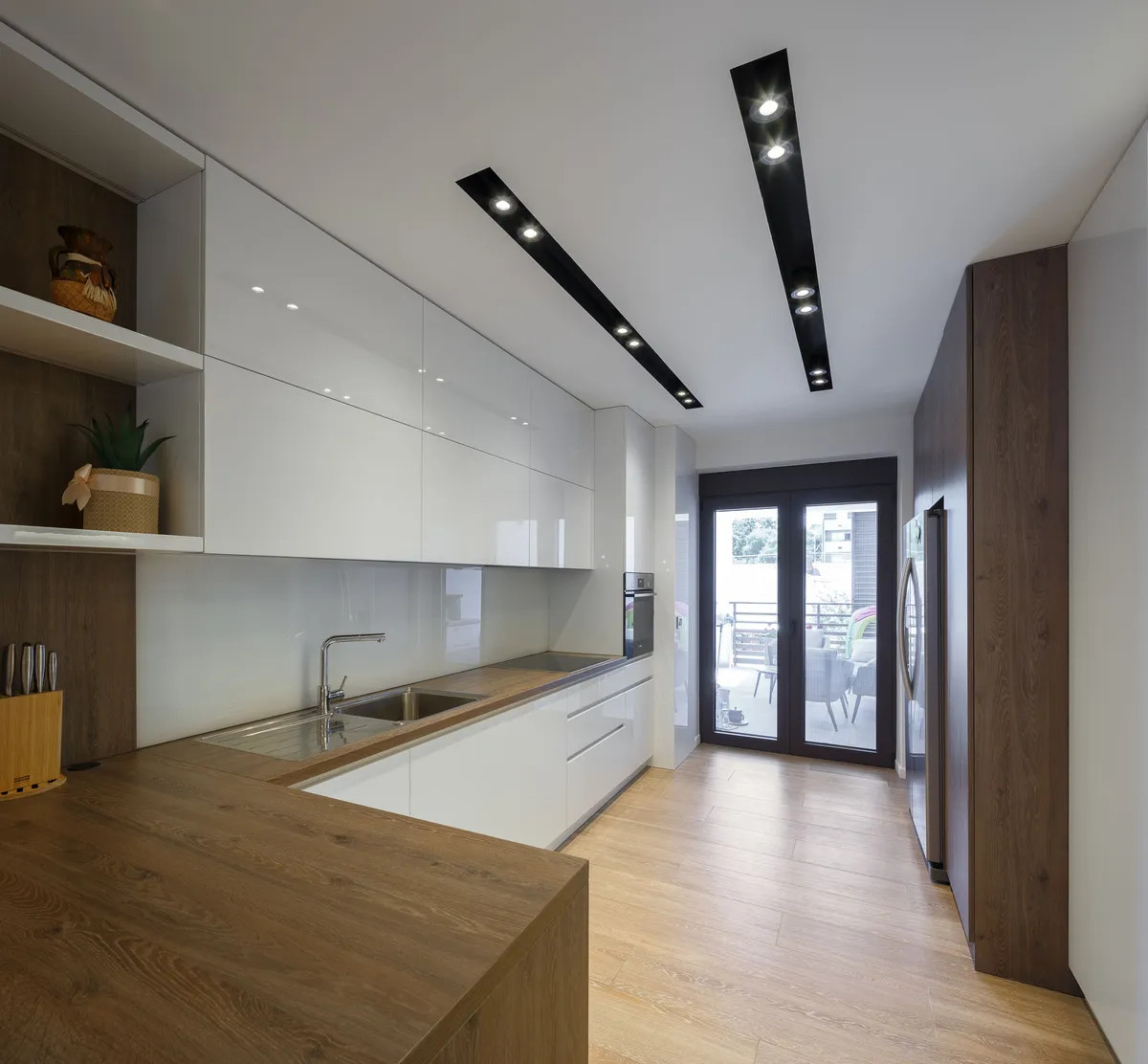A sleek modern kitchen featuring wooden floors and bright white cabinets, creating a clean and inviting space.