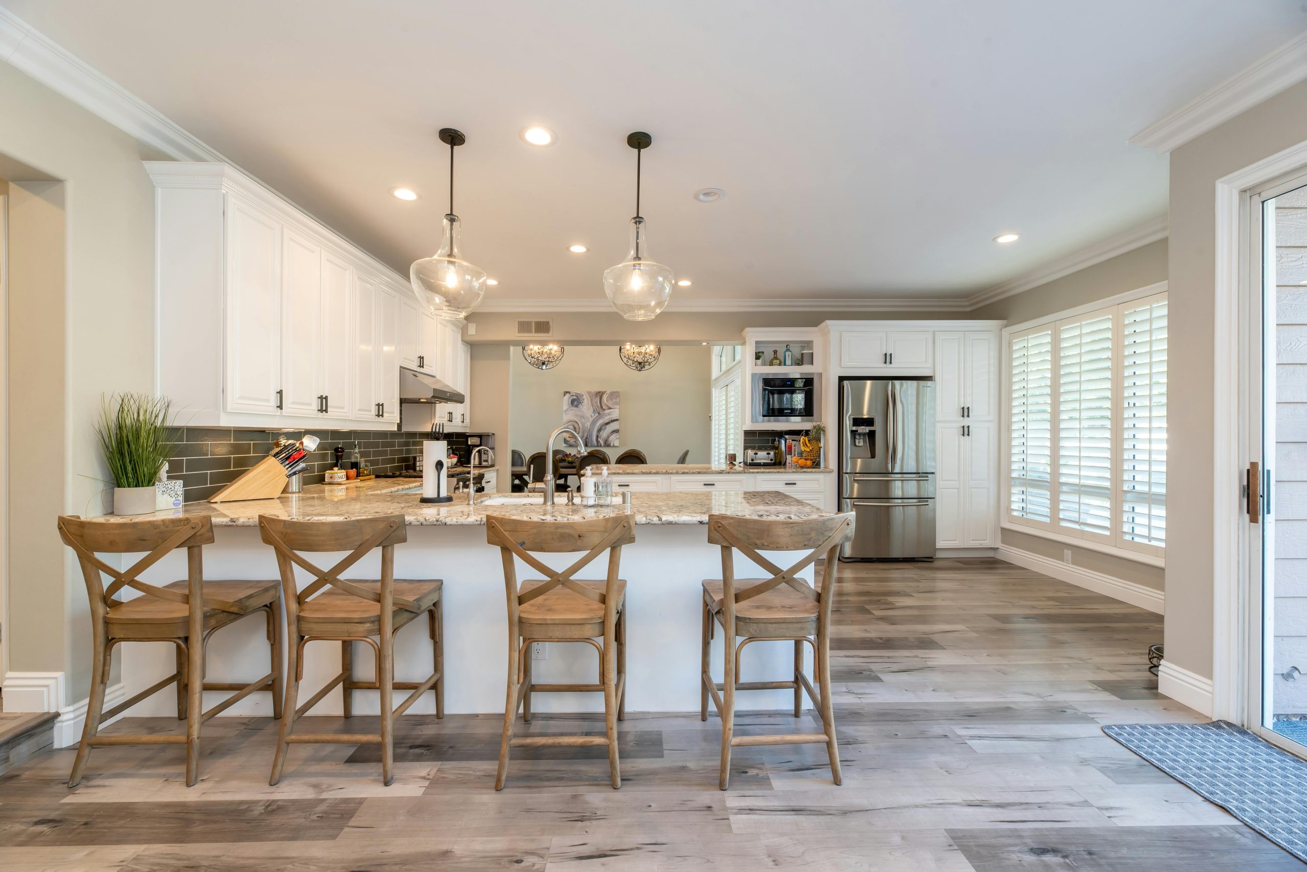A bright kitchen featuring white cabinets and warm wooden floors.