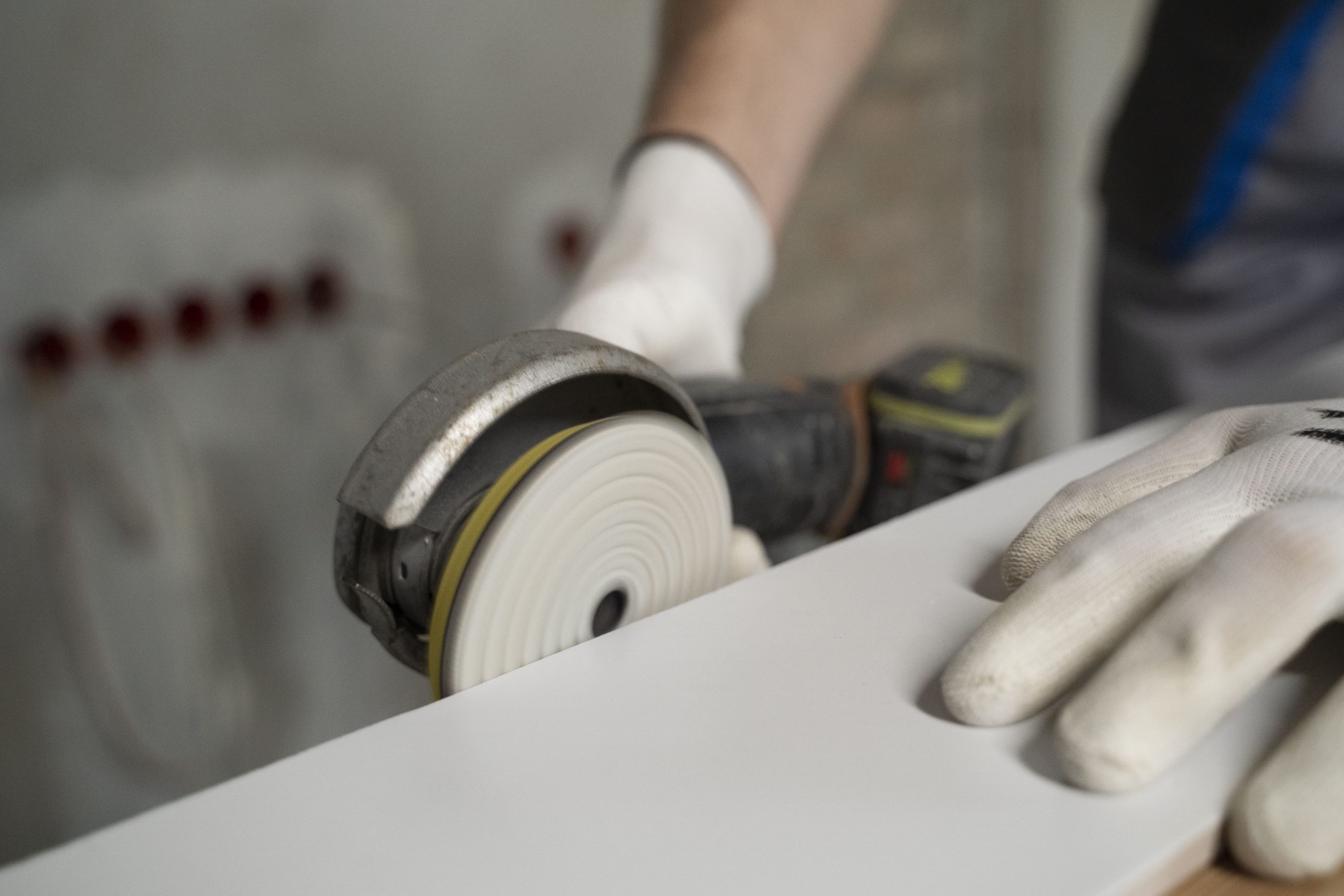 A person wearing a white glove operates a circular saw, focused on their task in a workshop setting.